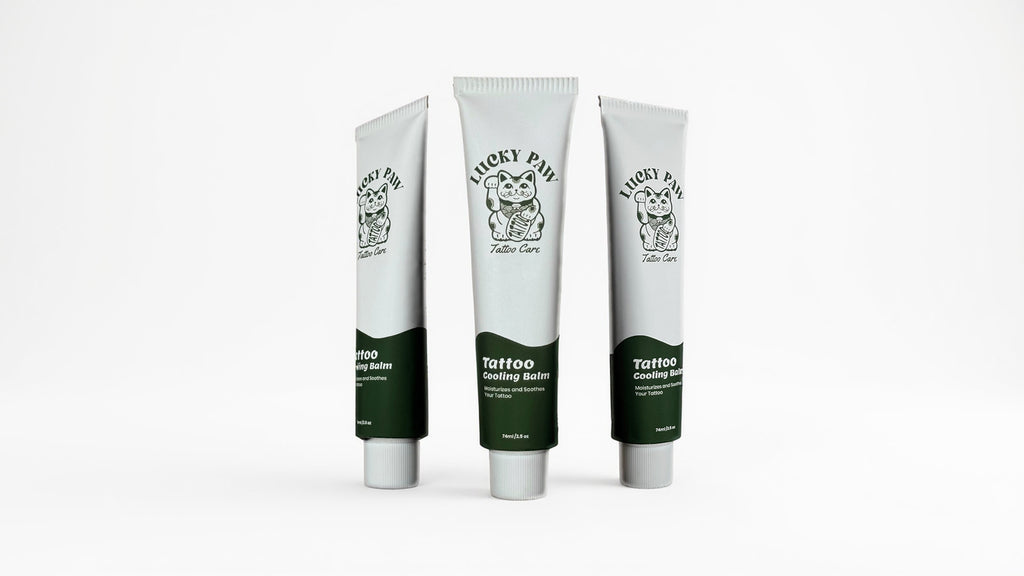Three tubes of Lucky Paw Tattoo Cooling Balm standing upright on a white background, showing the Lucky Paw Tattoo Care logo and green label design.
