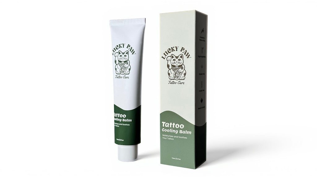 Lucky Paw Tattoo Cooling Balm tube and packaging box standing upright on a white studio background, featuring green and cream design with Lucky Paw logo.